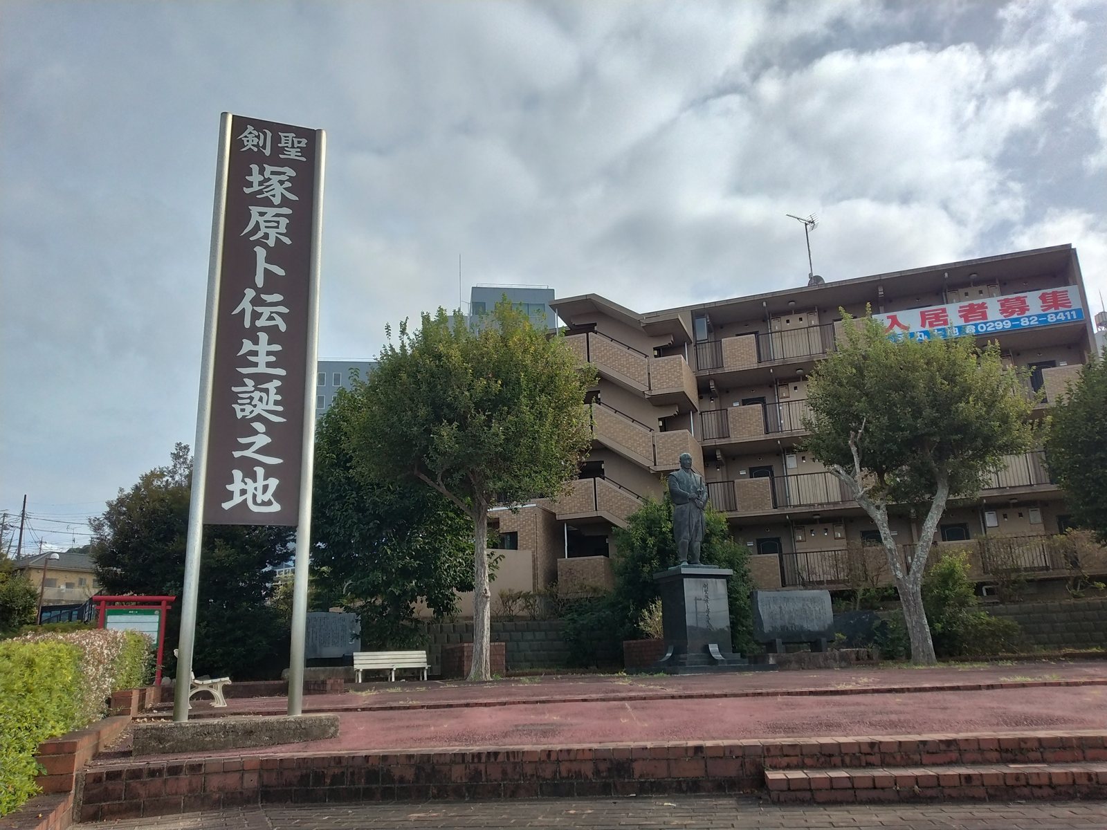 「剣聖 塚原卜伝生誕之地」の標柱。奥に銅像が見える