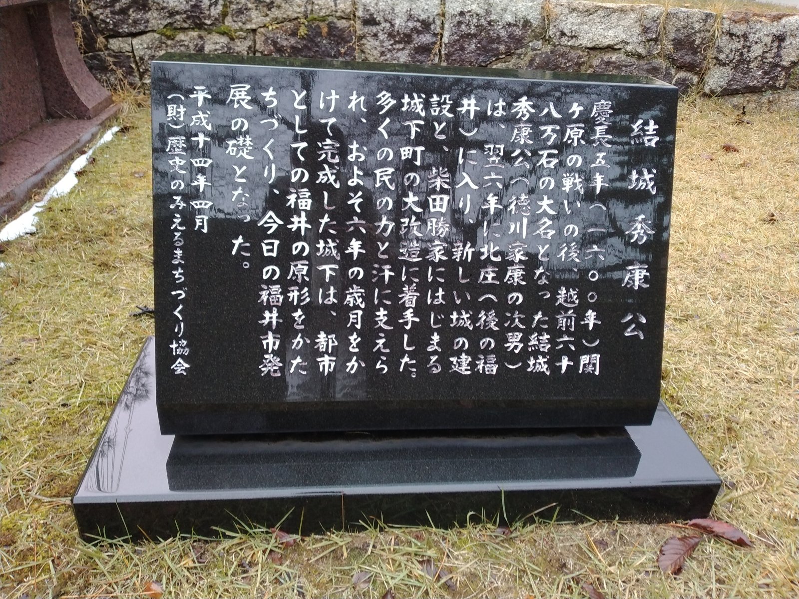 像の脇に立つ説明碑。城と城下町の由来が刻まれている