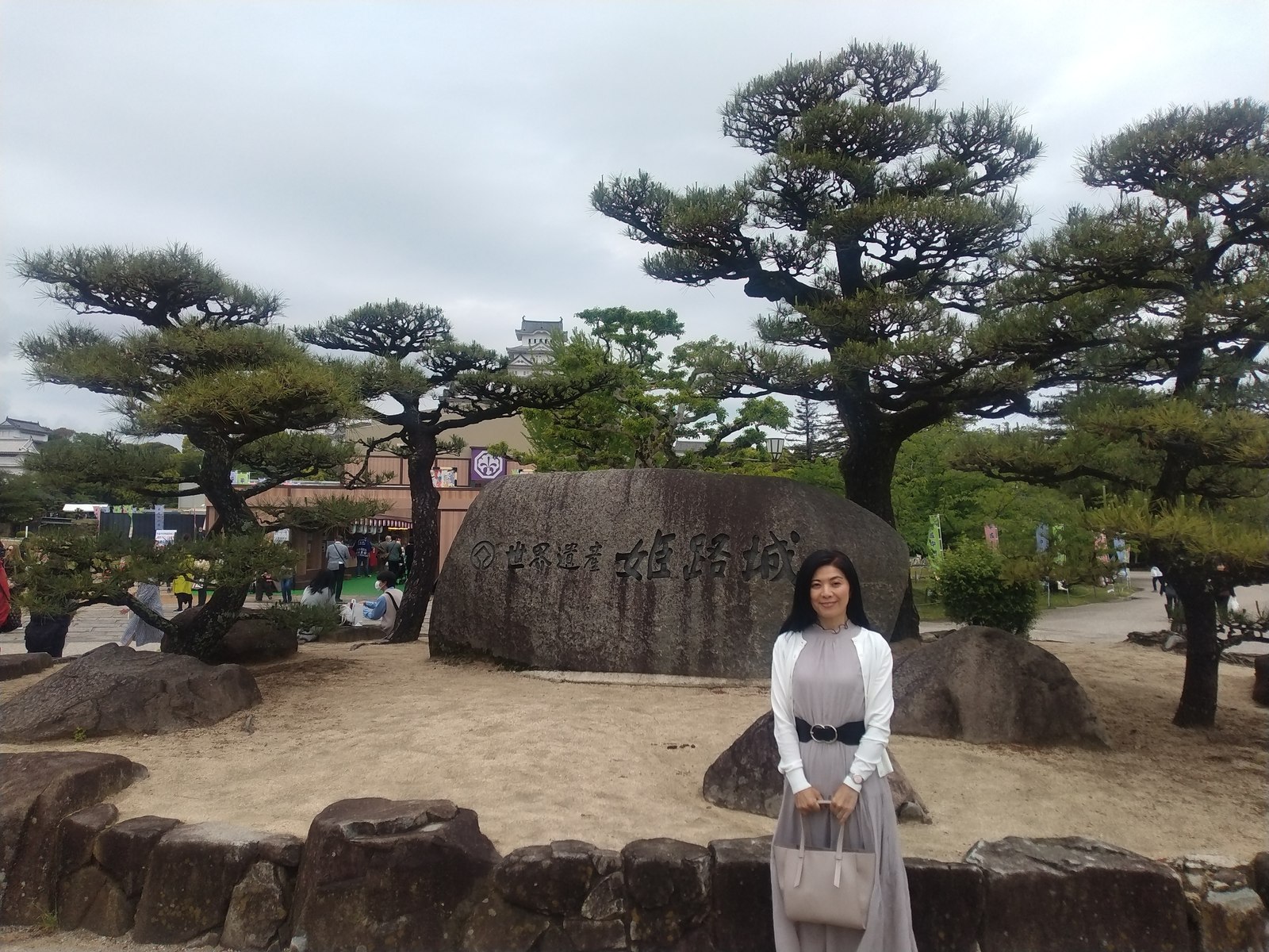 「世界遺産姫路城」の石碑前に立つ人物と松の庭園
