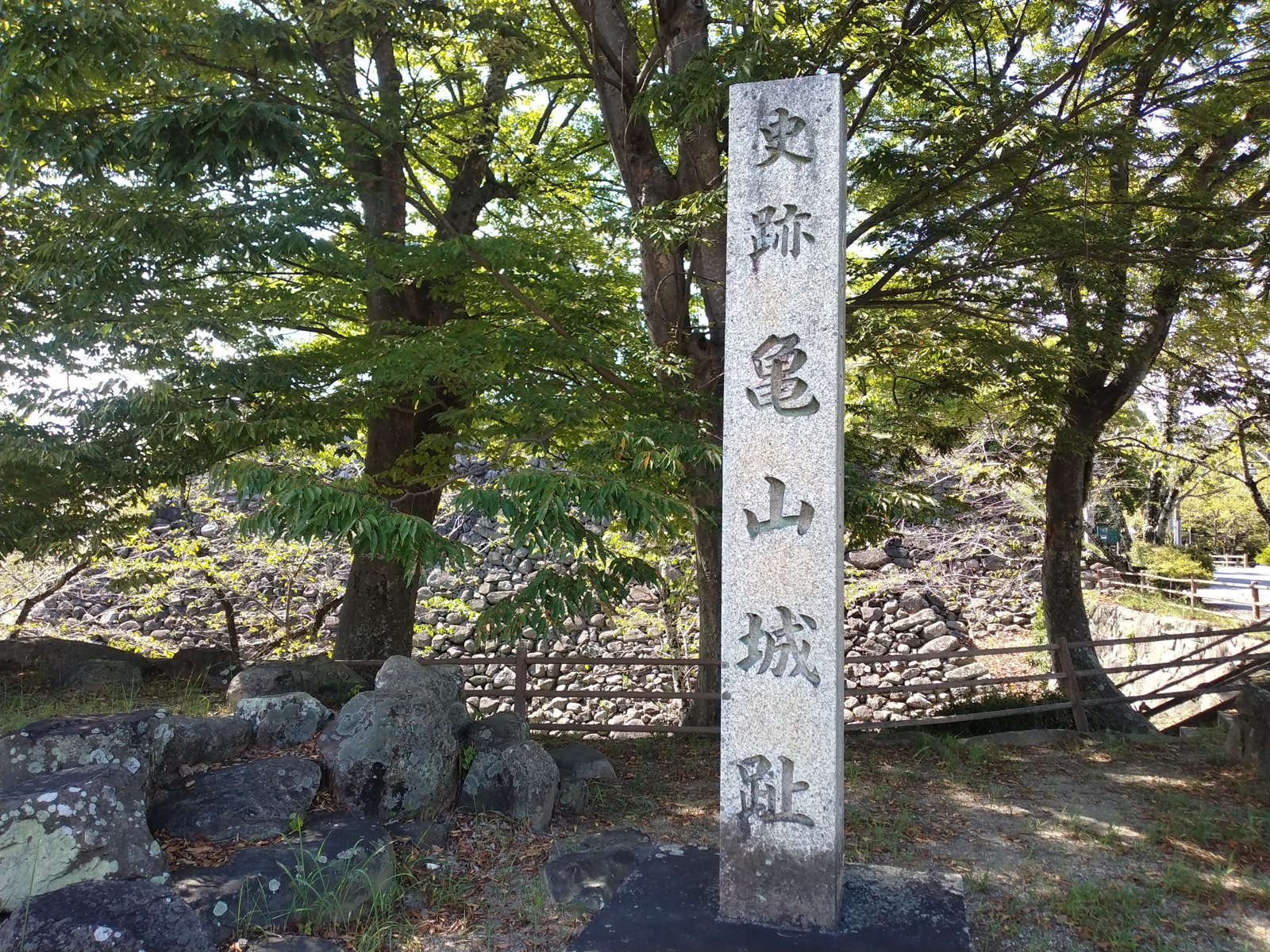 「史跡 亀山城趾」の石標。背後に本丸の石垣が崩れかけたまま残る