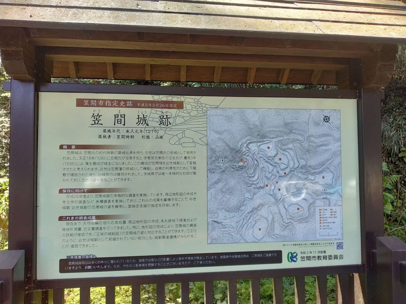 笠間市教育委員会の案内板。縄張図と地形図が並び、調査の経過まで書き込まれている。