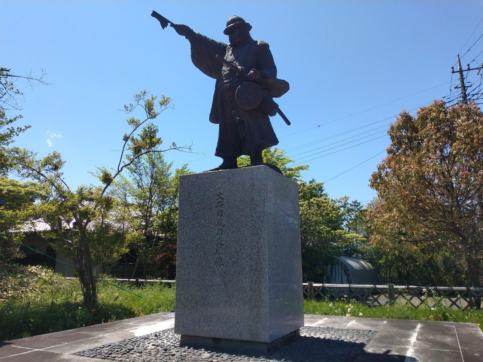 大石内蔵助良雄像。陣笠をかぶり、采配を掲げ、腰に陣太鼓を提げている。討ち入りの場面である。