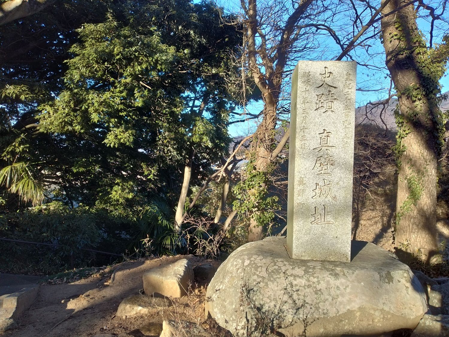 「史跡 真壁城址」の古い石柱。自然石の台の上に立っている。