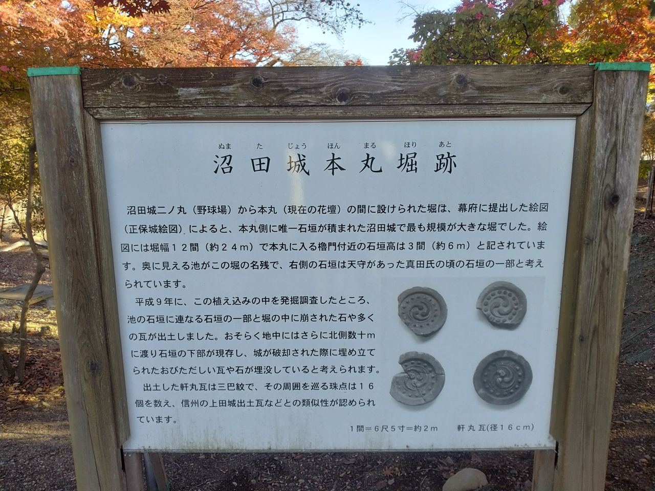 本丸堀跡の案内板。発掘で出土した三巴紋の軒丸瓦などが図示されている