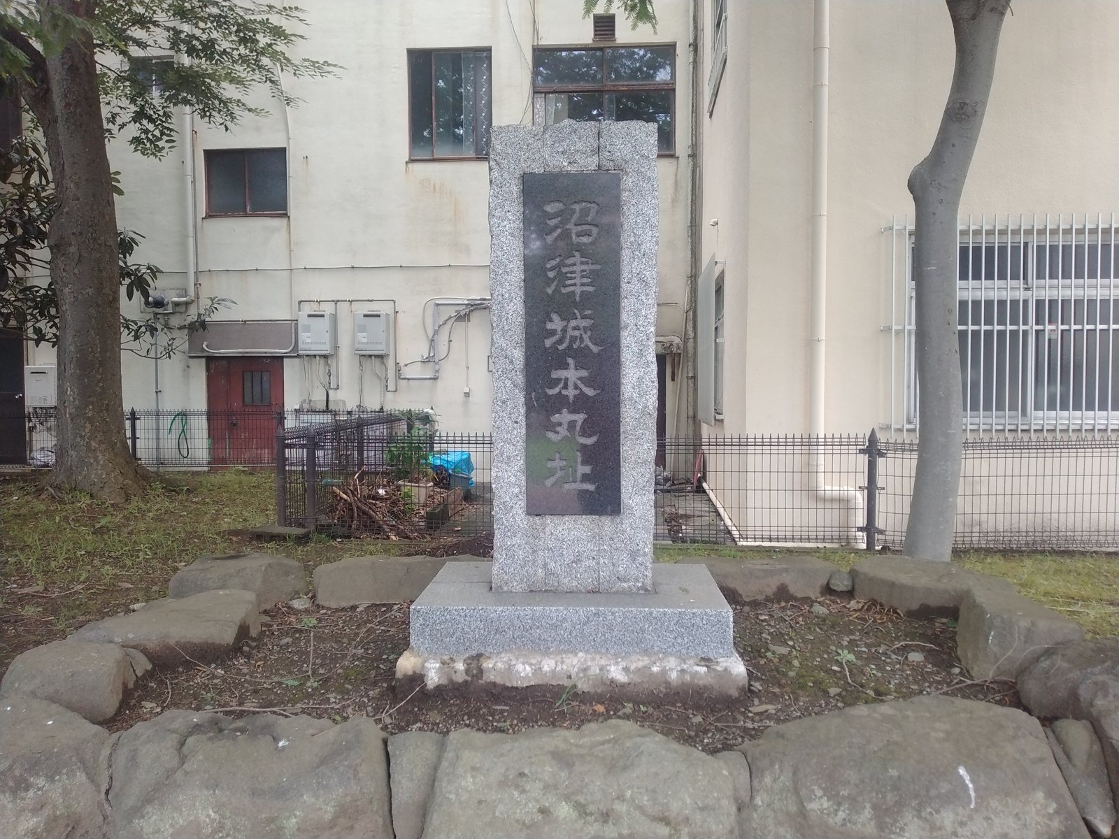 「沼津城本丸址」の石碑。周囲の石は三枚橋城の石垣に使われていたもの