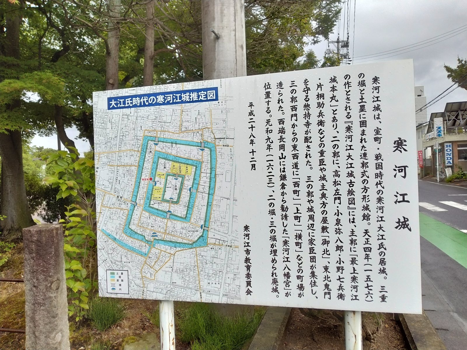 説明板は生活道路の脇に立っている。案内図の「現在地」の赤い点が、いまの町と昔の城を重ねてくれる