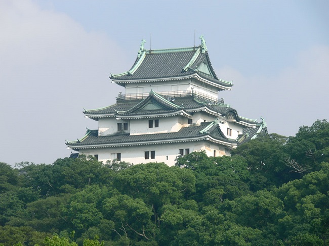 和歌山城の天守。緑の山の上に白い壁と黒い屋根が重なって見えます